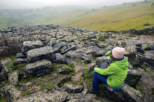 A bag for life makes for an ideal seat on the very wet and rugged terrain of Malham Cove, in January 2024.