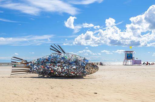 Pärnu, Estonia - July 14, 2022: Giant fish shaped wire trash container for collecting plastic and other waste on the beach.
