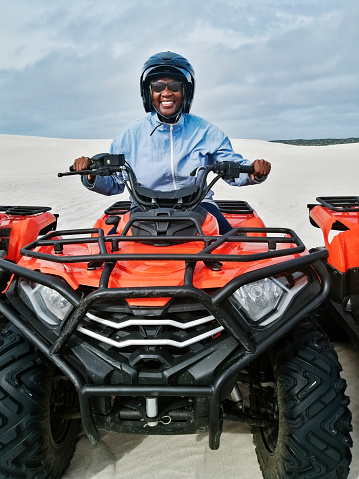 Portrait of active senior woman enjoying riding a quad bike and having an adventure in desert safari