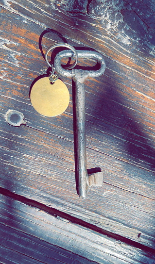 Silver key with blank tag wooden background. space for your text