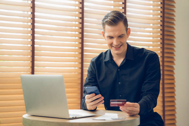 istock Young man using laptop with credit card for internet banking. Unveiling 1912019169