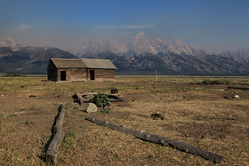 A scenic view of an old wooden cabin in a field in Grand Teton National Park