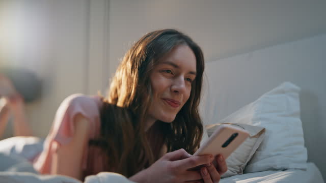 Pretty girl browsing social media in bed closeup. Happy young woman resting home