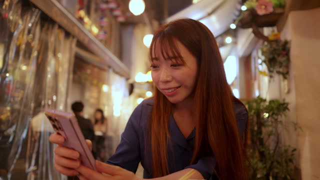 Woman using smart phone at outdoor Izakaya bar after work