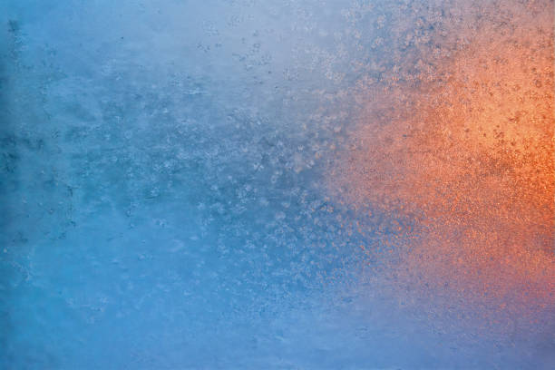 Natural background with white frost on the frozen window glass in the cold winter day front view close up.
