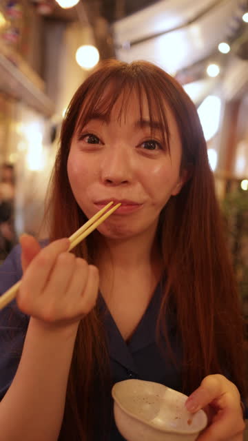 Woman eating food at outdoor Izakaya bar after work