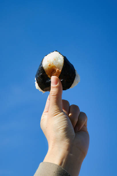 Onigiri held up against the clear blue sky