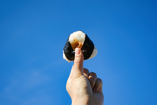 Onigiri held up against the clear blue sky