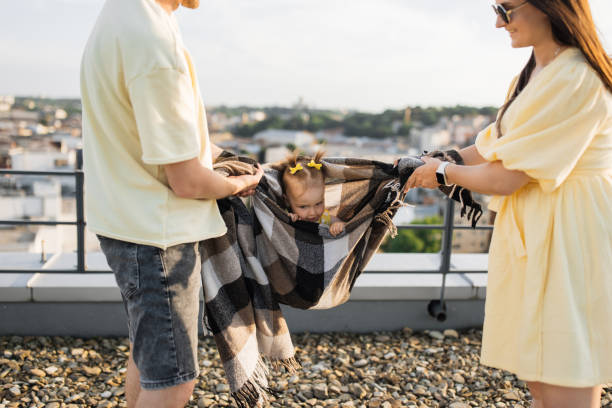 istock Playful parents holding blanket with daughter sitting inside 1912105006
