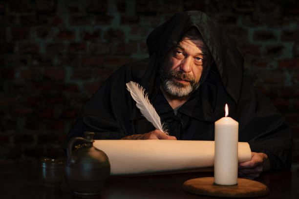 istock An old monk in a cell by candlelight writes a message on parchment with a goose quill, a scribe of holy scriptures. 1912105195