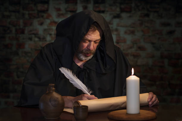 istock An old monk in his cell writes a message on parchment with a goose quill pen by candlelight. 1912105210