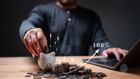People, holding coins, diligently nurture their wealth through piggy banks, a symbol of savings and finance, navigating the challenges of inflation and banking for sustained financial growth.