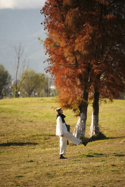 A woman is playing happily under the red maple tree