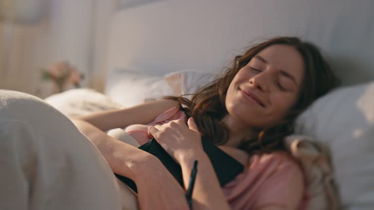 Peaceful girl holding diary in bed closeup. Smiling happy woman closing book