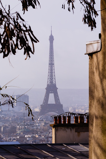 La Torre Eiffel vista desde Montmartre envuelta por la ciudad de París (Francia). El icónico monumento se ve tras las chimeneas.