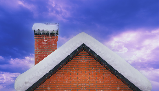 Roof and brick chimney covered with snow in winter