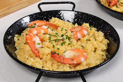Spanish dish paella with seafood in traditional pan, view from above.  Isolated on a white background.