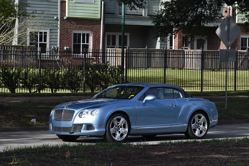 Houston, TX USA 7-27-2023  A portrait of a blue Bentley Continental convertible sedan cruising in the downtown district of Houston