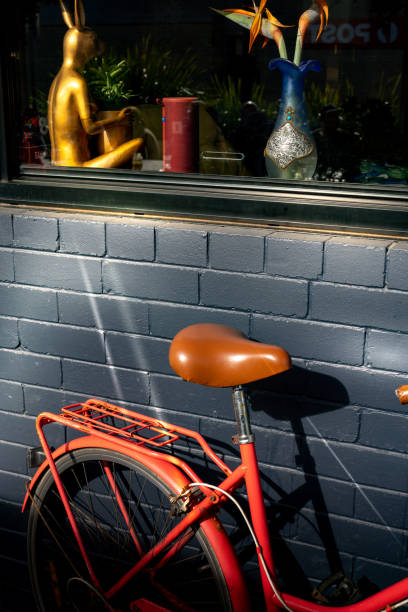 an orange bicycle sitting next to a blue brick building with statues