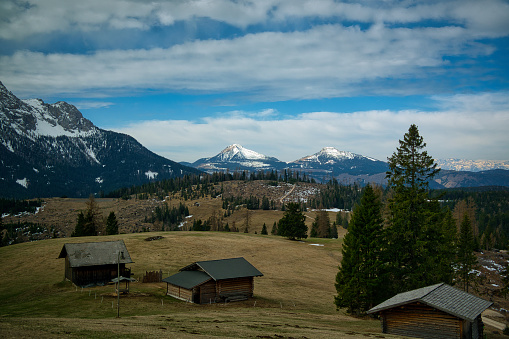 A scenic view of small cabins nestled in a vast field surrounded by lush mountains.