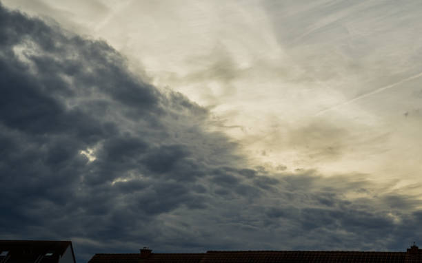 istock Ominous rainclouds in lighting sky over roofs 1912329387