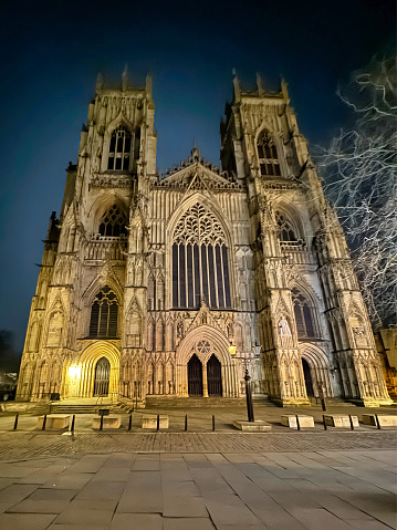 An awe-inspiring Gothic cathedral illuminated by majestic stained-glass windows at night, towering majestically against the night sky