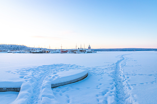 Frozen lake, pier, steamships and footprints on the ice.