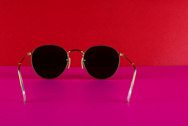 Classic metal framed sunglasses on a red background and pink base