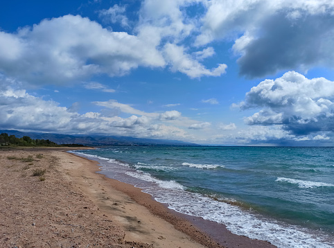 Cumulus clouds over the sea. Dramatic seascape. Waves on the shore. Kyrgyzstan, Lake Issyk-Kul