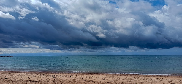 Cumulus clouds over the sea. Dramatic seascape. Waves on the shore. Kyrgyzstan, Lake Issyk-Kul.