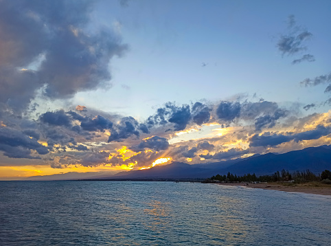 Cumulus clouds over the sea. Dramatic seascape. Waves on the shore. Kyrgyzstan, Lake Issyk-Kul