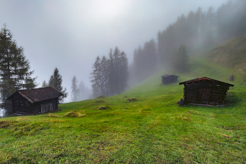 Mountain wooden haylofts in the Stubai Alps with fog in the background