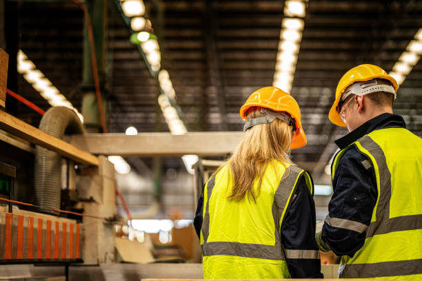 istock back of Factory engineer workers standing to control panel switch. people works at heavy machine at industry factory. with machinery equipment plant technology. smart industry worker operating. 1912433815