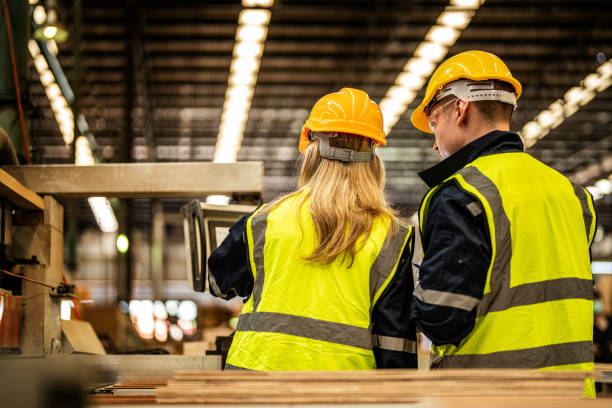 istock back of Factory engineer workers standing to control panel switch. people works at heavy machine at industry factory. with machinery equipment plant technology. smart industry worker operating. 1912442114