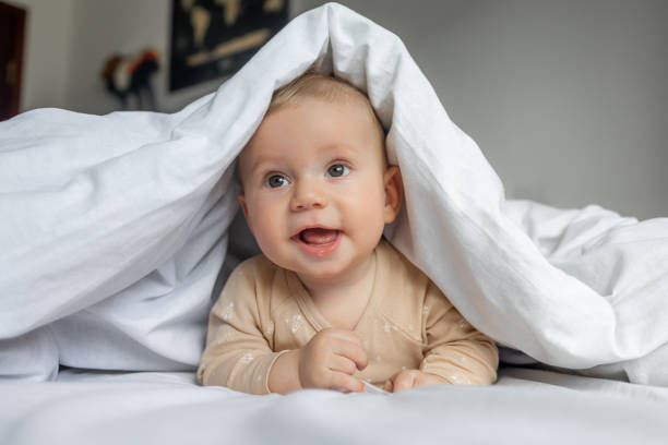 istock Wonderful babe plays on the bed in a light sheet, hiding under a white blanket,playing with mommy hide and seek 1912468433