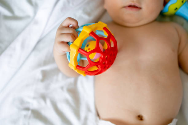 istock baby is lying holding and playing with a rattle on a white background, closeup toy selective focus 1912468451