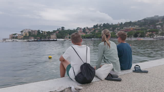 Three teenagers sitting at the Rapallo pier