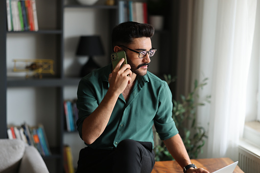 Portrait of smiling israeli man talking on phone at home