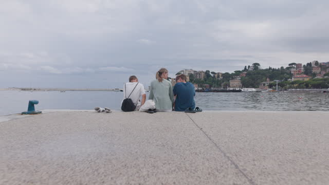 Three teenagers sitting at the Rapallo pier