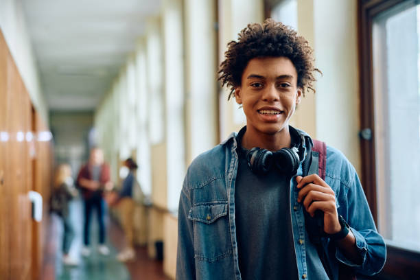 istock Happy black high school student in hallway looking at camera. 1912510467