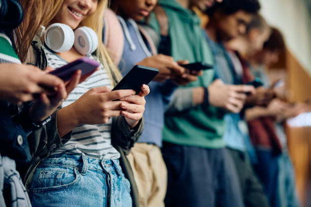 istock Close up of high school students using smart phones in a hallway. 1912512575
