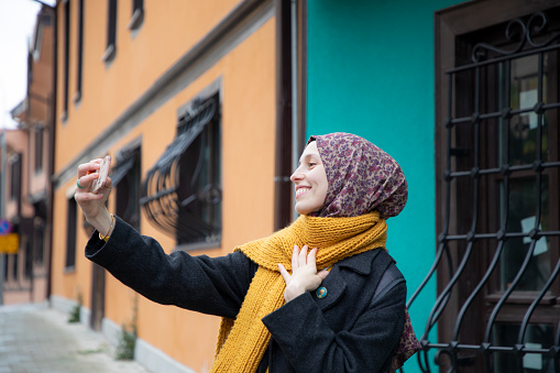 Young Muslim tourist woman taking selfie in front of historical Odunpazarı houses in Eskişehir