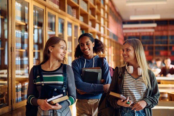 istock Happy female high school students talking in library. 1912516271