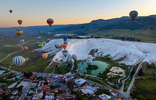 Hot air balloons and Natural travertine pools at sunrise in Pamukkale,
