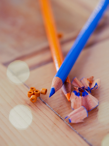 Duo of wooden pencils crusaders with wood chips and orange tiny balls on a glass