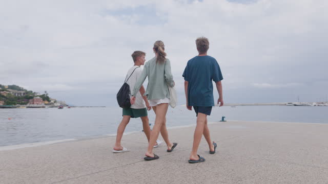 Three teenagers walking at the Rapallo waterfront promenade