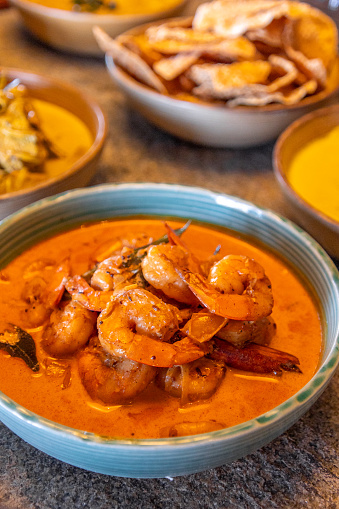 Sri Lankan prawn curry meal with variety of curry dishes served in restaurant with colorful bowl crockery