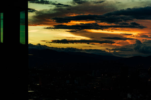 Panoramic view of part of Mexico City, from inside a skyscraper. The image is during twilight where warm tones are seen in the sky and clouds.