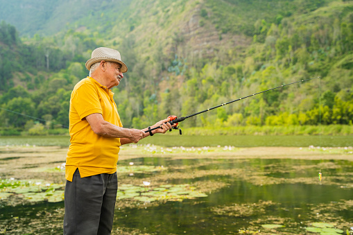 senior adult fishing by the lake on a sunny day, while enjoying his retirement