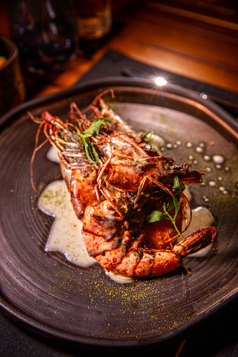 Boiled tiger prawns in a plate on a black stone background. Red shrimp. Top view, flat lay,